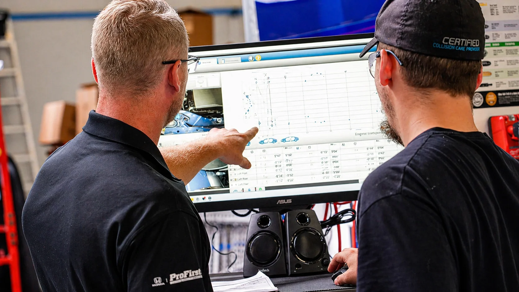 Technicians reviewing vehicle measurement data and repair analysis on computer screen