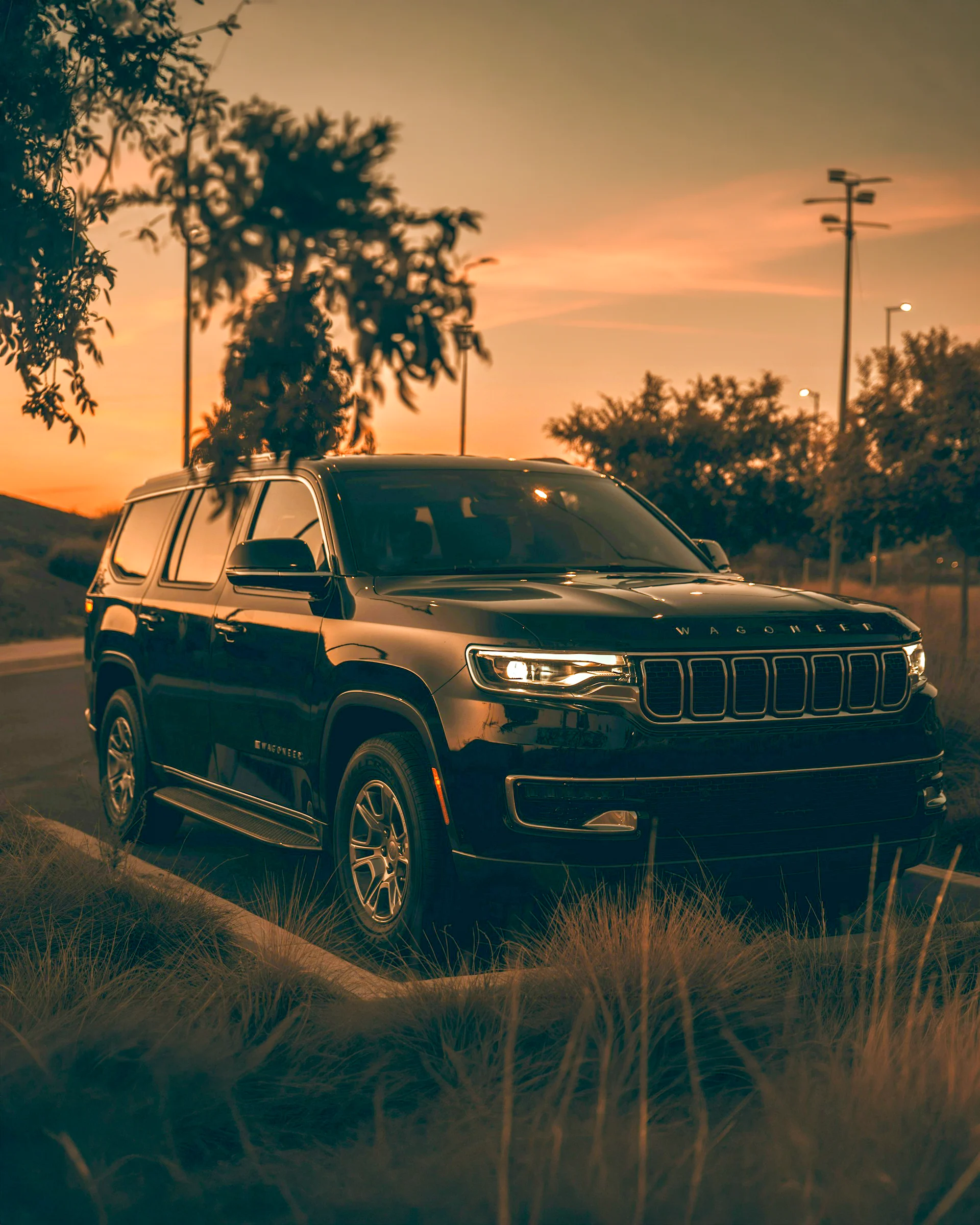 Jeep Wagoneer SUV parked at sunset with headlights on