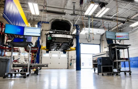 Vehicle raised on lift with diagnostic computers and scanning equipment in a collision repair facility